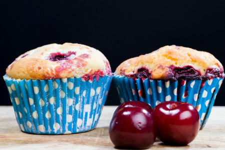 cherry muffins in white sugar topping on wooden table, fresh soft pastry productの写真素材