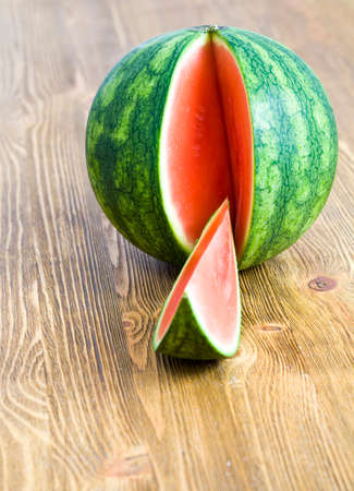 sliced small red and juicy watermelon on a wooden board, details of a plantの写真素材