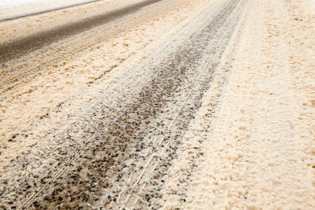 details of snow-covered road in the winter, traces of cars and tracks from transport, close-up on the roadwayの写真素材