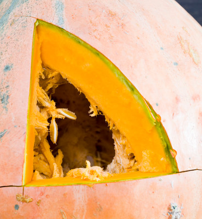 a triangle carved into a large pumpkin while cooking vegetables for food or preparing a lamp for Halloween, close-up indoorsの写真素材