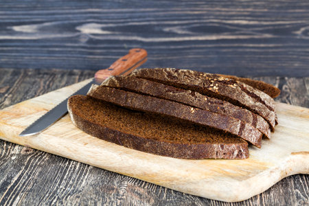 black rye bread cut with a knife on a cutting Board, close-up of traditional food