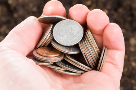the hand of a man with coins that rush into quality soil, agriculture with land on the ground of...