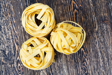 several twisted long pasta made from durum wheat flour, close-up of raw solid food on a cutting...