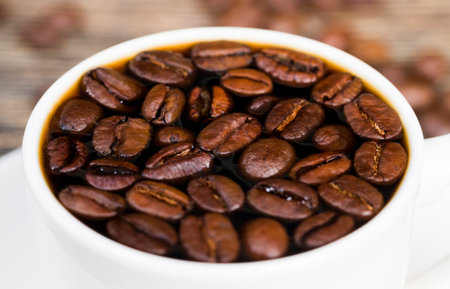 beautiful roasted coffee beans with warm freshly made coffee in a white Cup, whole grains for making...