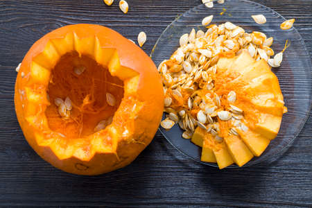 sliced and gutted orange pumpkin on the kitchen table, close-up of vegetables prepared for food or servingの写真素材