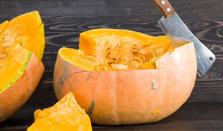 cut into pieces a ripe orange pumpkin in October, a close-up of food and inventory for the Halloween holidayの写真素材