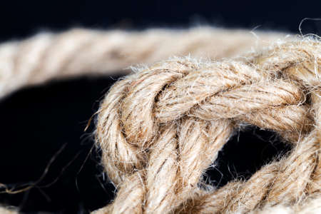thick linen gray rope tied into knots, details and structure of the rope close-up, used for different purposesの写真素材