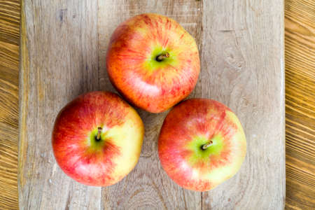 red ripe apples on a wooden surface, close-up of the harvest of sweet fruitの写真素材