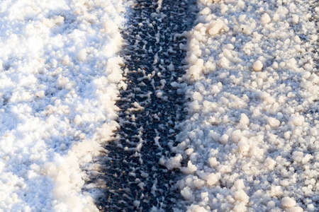 tracks and track on a winter road that is covered with snow in frosty winter weatherの写真素材