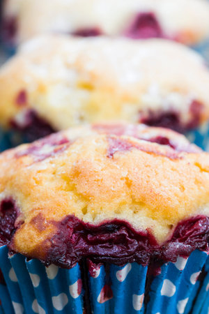 three delicious sweet muffins with cherry berries inside, food ready for eating close up, made in a factoryの写真素材