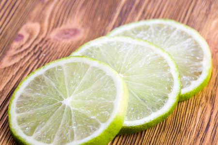 a few sliced green slices of citrus lime on a wooden Board, in large chunksの写真素材