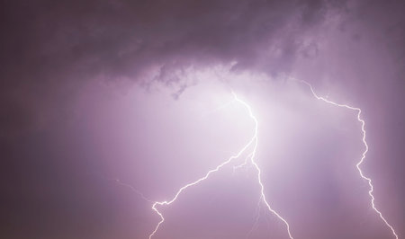 large lightning discharge in the night sky during a thunderstorm, landscape with sky illuminated by...