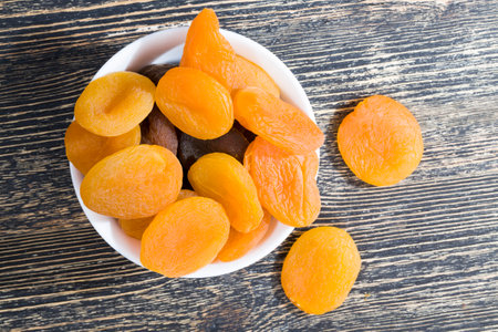 dehydrated dried ripe apricots, orange, traditional, useful the sweetness of the dried fruit in a round white glass plateの写真素材