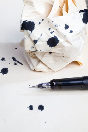 a dirty old fountain pen and black stains ink blotches on an old yellowed piece of paper