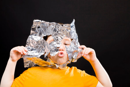 the boy creates different things from foil, including hats that he puts on his head for protectionの写真素材