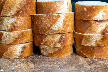 a wheat baguette cut into pieces, pieces from a cut fresh baguette made of wheat flour are lying on...