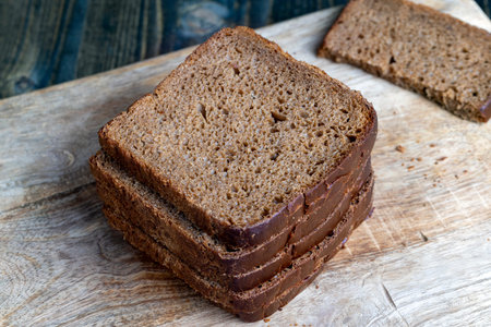 sliced rye bread on a wooden table, soft fresh loaf of bread cut into pieces on a cutting board