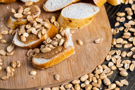wheat fresh baguette and peanut paste, making breakfast of bread and peanut butter with pieces of...