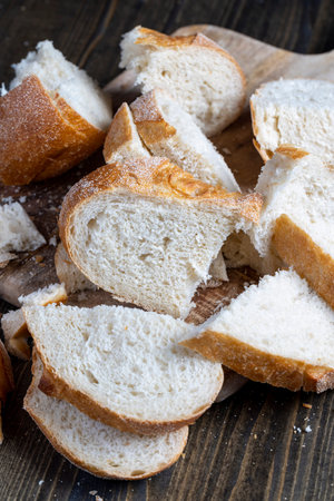 sliced loaf of bread on a cutting wooden board, rye loaf of bread cut into pieces while cooking food