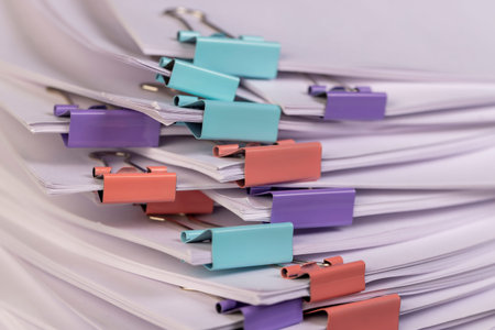 white blank sheets of paper are connected by multicolored metal clips, stacked sheets of paper for...