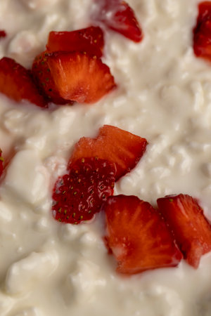 cottage cheese with sour cream and fresh strawberries, white sour-milk cottage cheese with ripe sweet strawberries cut into pieces, close upの写真素材