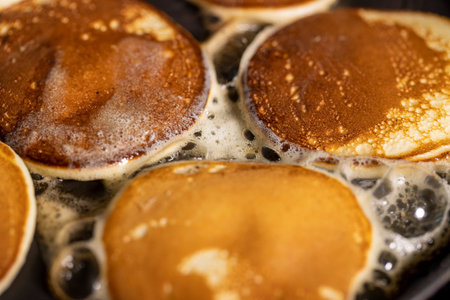 baking small pancakes with butter in a frying pan, hot metal pan while cooking pancakes with butter