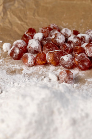 candied fruits of kumquat boiled in sugar syrup in powdered sugar, sweet dehydrated candied fruits of kumquat in white powdered, close upの写真素材