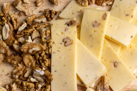 Sliced piece of milk cheese with walnuts, crushed and chopped walnuts with hard cheeseの写真素材