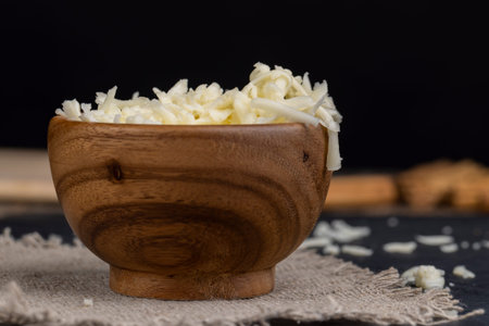 grated cheese in a wooden bowl, grated cheese for cooking in a wooden bowl in the kitchen