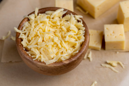 grated yellow semi-hard cheese with holes, fresh cheese from milk with pieces for cookingの写真素材