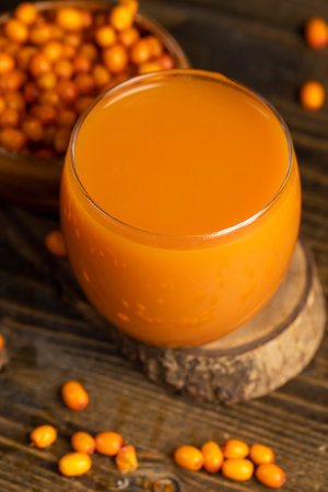 frozen orange sea buckthorn berries and a glass of sea buckthorn juice, a glass of natural orange juice and frozen sea buckthorn berries, close upの写真素材