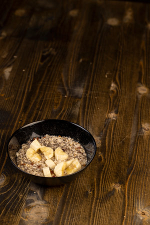 ripe banana in cooked oatmeal porridge, boiled oatmeal porridge with chia seeds, berries and fresh banana, closeup, side viewの写真素材