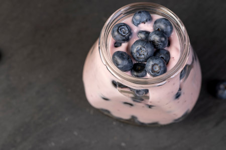 blueberries and milk blueberry yogurt, a black slate table and a jar of yogurt with natural ingredients and blueberry flavorの写真素材