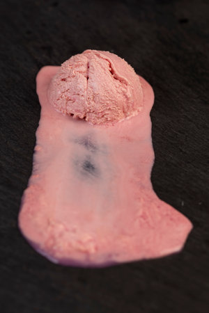 melting pink ice cream on a black board , sweet cold pink ice cream with strawberry flavor, closeupの写真素材
