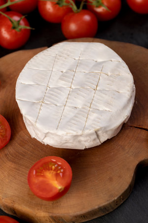 cheese and small red tomatoes, a piece of soft cheese and some small red round tomatoes on the table, closeupの写真素材