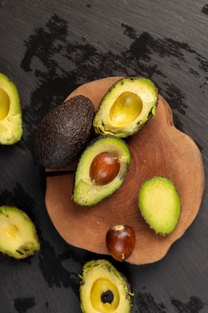 cut avocado with green flesh on a wooden cherry board, top viewの写真素材
