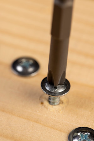 pine board and steel screws for wood, silver self-tapping screws for wood on the board, close upの写真素材