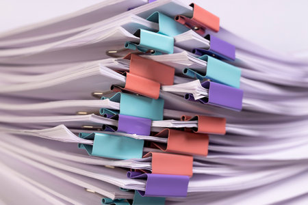 a large number of white blank sheets of paper are connected by multicolored metal clips, stacked sheets of paper for documents are joined togetherの写真素材