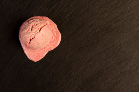 melting ice cream on a black slate, sweet cold pink ice cream with strawberry flavorの写真素材