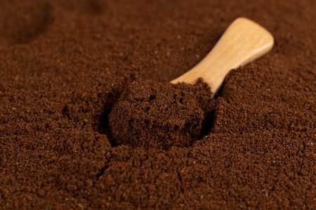 ground coffee and a small wooden spoon, a large number of roasted ground coffee beans in powder and a wooden spoonの写真素材