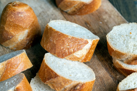 a wheat baguette cut into pieces, pieces from a cut fresh baguette made of wheat flour are lying on...