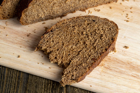 Sliced black rye bread on a board, plain fresh bread cut into pieces on a board