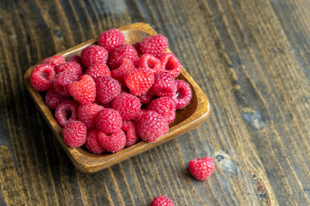 Ripe raspberries on the table, raspberries in a wooden bowl and on a board