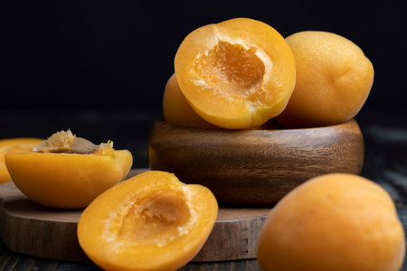 Orange-colored ripe apricot cut into pieces, apricot halves on a wooden tableの写真素材