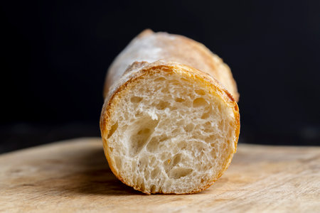 Sliced wheat baguette on a board, wheat flour food on the table during cookingの写真素材