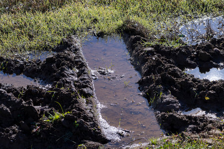The road in the field is completely flooded with water after traffic, off-road in the field is not...