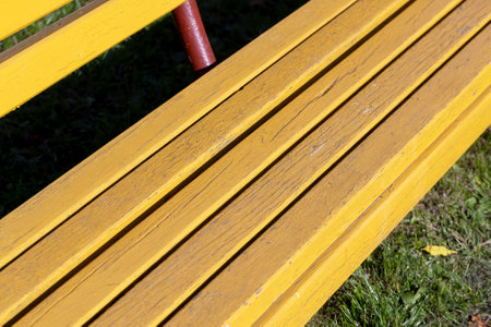 Benches installed in the park for recreation, painted with yellow paint benches in the park on a field with mown grassの写真素材