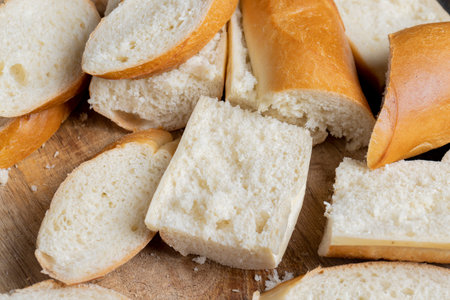 a wheat baguette cut into pieces, pieces from a cut fresh baguette made of wheat flour are lying on the boardの写真素材
