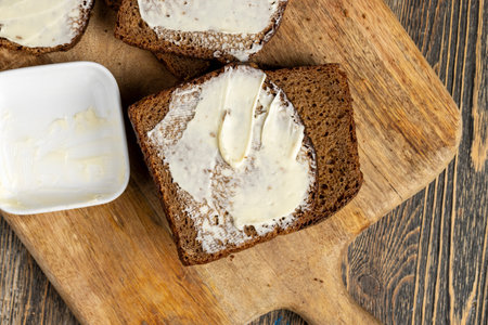 Black rye bread with butter, butter spread on bread on the tableの写真素材