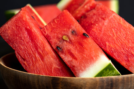 Sliced red and ripe watermelon on the table, juicy pieces of watermelon sliced on a black boardの写真素材